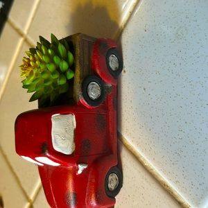 A porcelain red truck with a fake cactus in the back